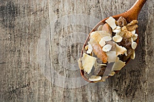 Muesli and dried fruit in wooden spoon on wooden table. Top view.