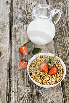 Muesli and a jug of milk for breakfast. Granola with strawberry