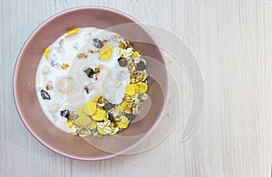 Muesli with on a pink plate, top view. Muesli with fresh milk, yogurt or kefir. Muesli is made from oatmeal, a mixture