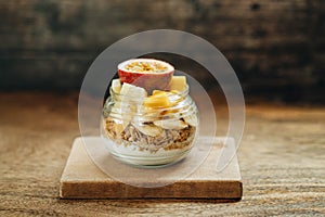 Muesli with yoghurt and tropical fruit at brown background