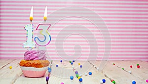 Muffin with cream and number 13 for a birthday on a pink background, copy space, holiday background. Happy birthday greetings