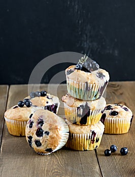 Muffin cupcakes with blueberries on a wooden background. Cupcakes decorated with berries Vertical photo