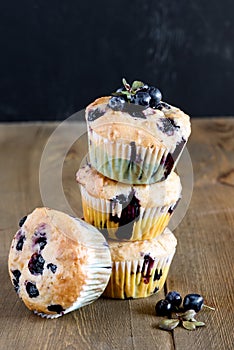 Muffin cupcakes with blueberries on a wooden background. Cupcakes decorated with berries Vertical photo