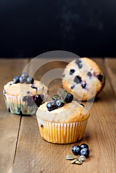 Muffin cupcakes with blueberries on a wooden background. Cupcakes decorated with berries Vertical photo