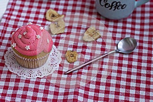 muffin is decorated with pink buttercream and sugar stars