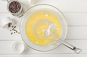 Muffin dough with chocolate chips in a bowl on a white wooden background. Recipe step by step. Top view