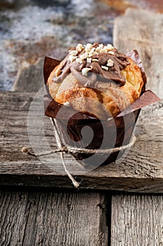 Muffin with milk chocolate and nuts on a rustic wooden background. Close-up