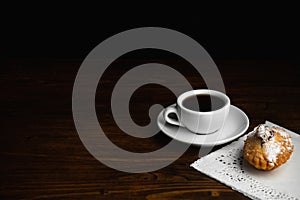 Muffin with white cup of coffee on a dark wooden background