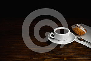 Muffin with white cup of coffee on a dark wooden background