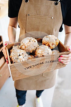 Muffins in a branded wooden box, held by a female baker