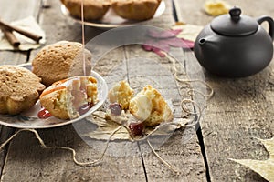 Muffins with jam on wooden background. Pouring jam on a cupcake