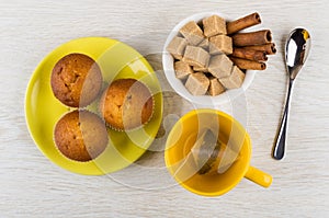 Muffins on saucer, teabag in cup, cinnamon and sugar, spoon