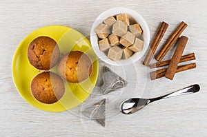 Muffins on saucer, teabags, sugar, cinnamon, teaspoon on table