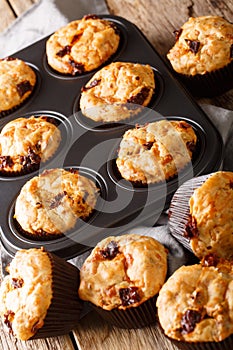 Muffins with sun-dried tomatoes and cheddar cheese close-up in a baking dish. Vertical