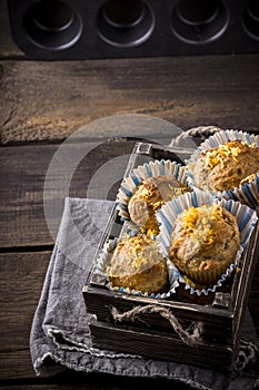 Muffins in a wooden box on wooden table.
