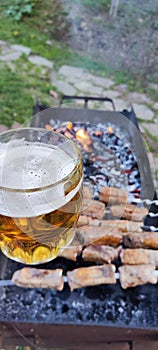a mug of beer on the background of a barbecue with kebabs