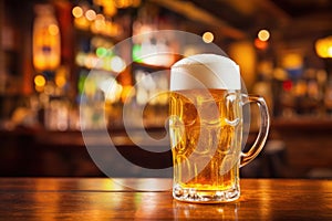 mug of beer with foam on table with bar counter in pub on the background