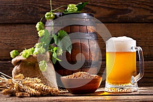 Mug of beer with green hops, wheat ears and wooden barrel