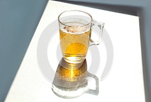 Mug of beer on the kitchen table, shadows from objects, close-up