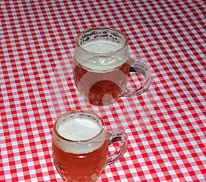 A mug of beer on a table covered with a red checkered tablecloth