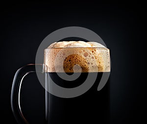 Mug of black beer or kvass on a black background. Foam close-up. Stock photo