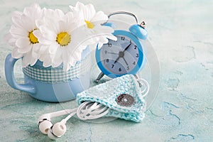 A mug, blue alarm clock and flowers