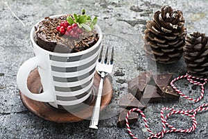 A mug cake for a festive New Year`s Eve snack with red white sweets in a striped red white mug on a gray stone