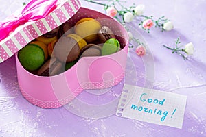 Mug cakes Macaron, leaf notebook inscription good morning on purple table top. The cozy breakfast. Copy space
