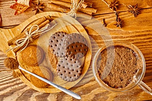 Mug of cocoa chocolate cookies and cinnamon sticks on wooden table.