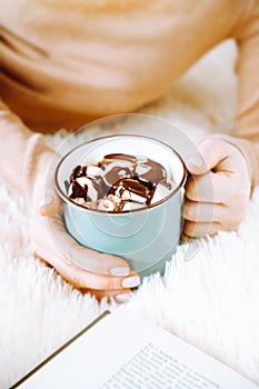 Mug of cocoa with marshmallows and chocolate in female hands