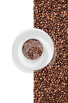 Mug of coffee beans on a white plate suraunded by coffee beans on the white background