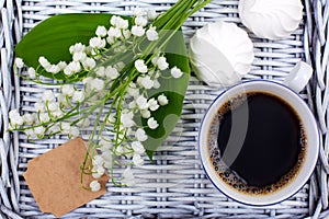 Mug of coffee, marshmallows and flowers lie on a blue table