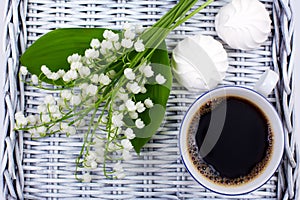 A mug of coffee, marshmallows and flowers lie on a blue table