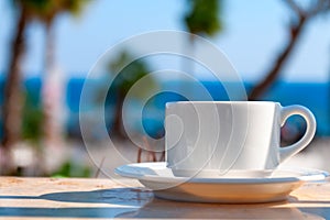 Mug with coffee on a table in a cafe on a background of palm trees