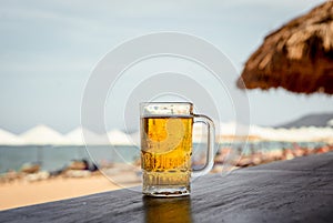 Mug of cold beer with foam on the table.