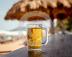 Mug of cold beer with foam on the table.