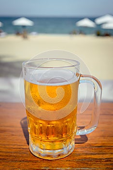 Mug of cold beer with foam on the table.