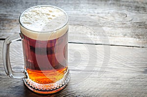 Mug with dark beer on the wooden table