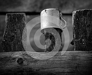 A mug on the fence. Rustic still life. Black and white
