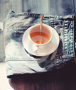 Mug filled boiling water and tea bag on blue jeans background. Process tea brewing in ceramic mug. Herbal green or black