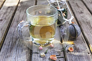 Mug of flavored green tea with rose buds and petals