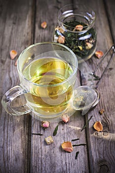 Mug of flavored green tea with rose buds and petals