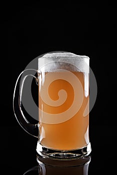 Mug of foamy beer isolated on dark background