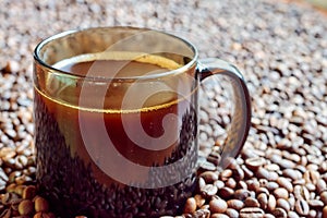 A mug of freshly brewed coffee stands on coffee beans