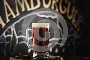 mug full of chopp, with dark chopp on a rustic table.