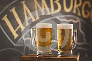 Mug full of chopp, with dark chopp on a rustic table.