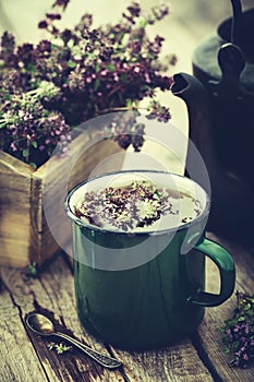 Mug of healthy herbal tea, old tea kettle and box of thyme flowers.