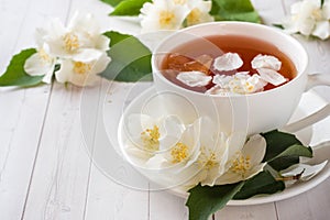 Mug of herbal tea with petals of Jasmine flowers on a light back