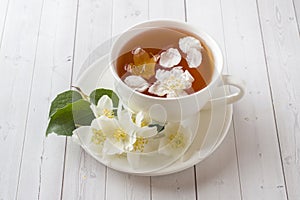 Mug of herbal tea with petals of Jasmine flowers on a light background.