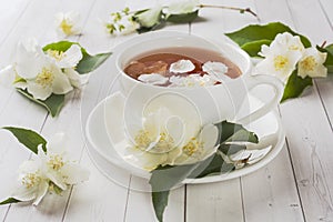 Mug of herbal tea with petals of Jasmine flowers on a light background.